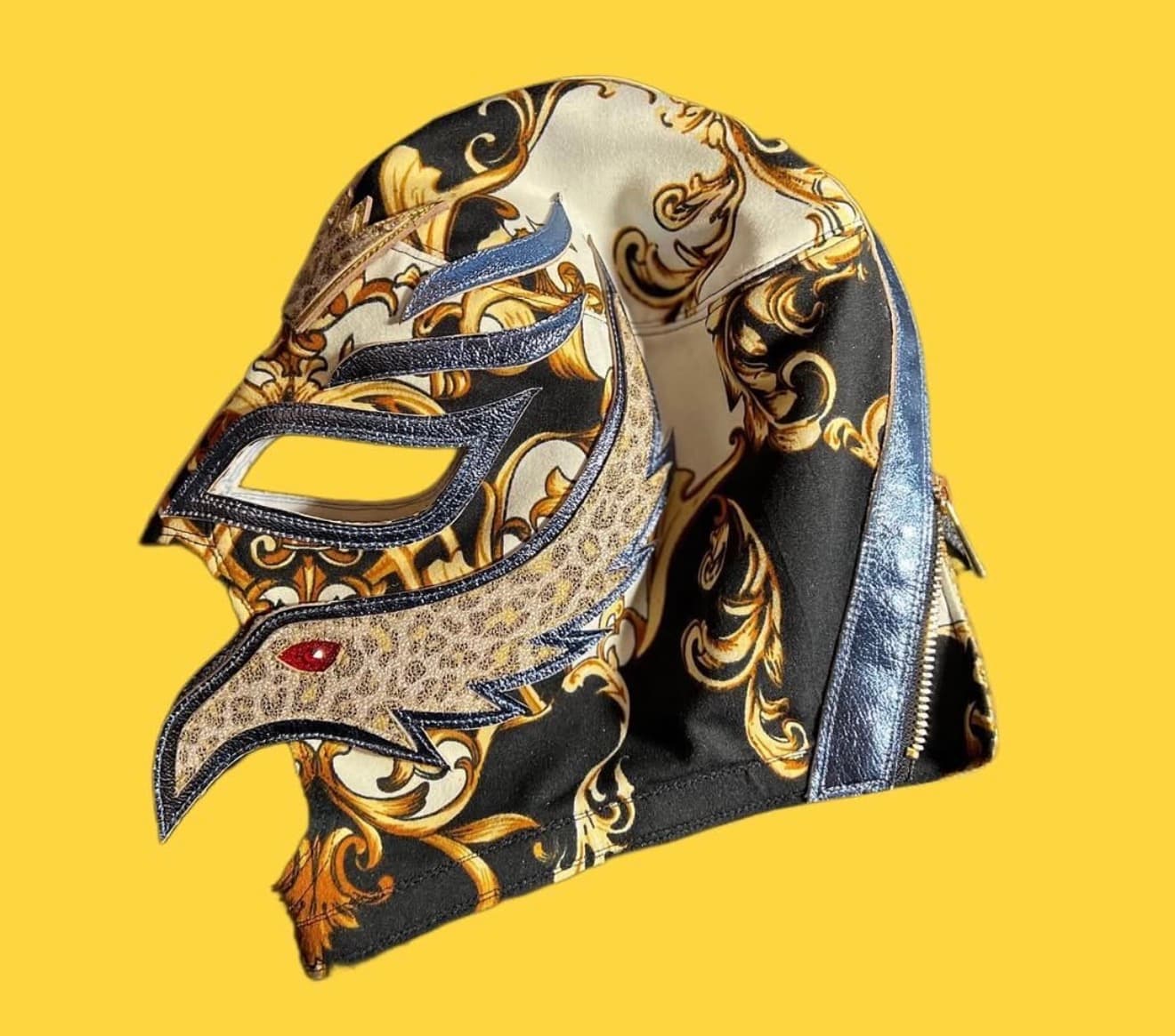 Ornate Lucha Libre mask featuring gold filigree, blue metallic accents, and a bird-like profile.